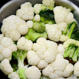 a pot of boiling water with salt and cauliflower and broccoli florets.