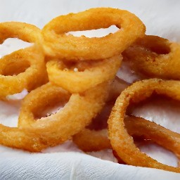 the onions are drained of extra oil on a plate lined with kitchen paper.