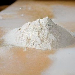 a quarter cup of bread flour is on the board to create a floured surface.