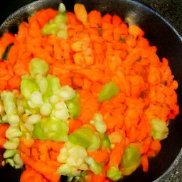 a skillet full of cooked onions, carrots, portabella mushrooms, and green bell peppers.