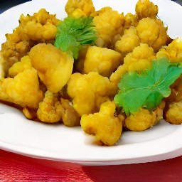 a plate of cauliflower, potato and onion curry with spices.