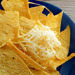 a bowl of corn tortilla chips topped with a mix of paprika, chili powder, cumin, onion powder, garlic powder, cayenne pepper, parmesan cheese, cheddar cheese and mont