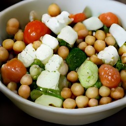a bowl of chickpeas, cucumbers, tomatoes, onions, feta cheese, ranch dressing and black pepper that are mixed together.