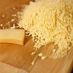 the parmesan cheese is shredded using a grater.