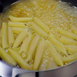 adding salt and penne pasta to the boiling water.