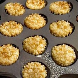 a muffin tin with cheese slices on top and chopped walnuts scattered over it.