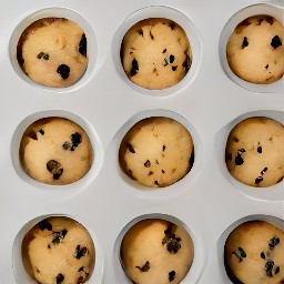 chocolate chip dough balls in muffin liners on a baking sheet.