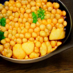 a dish containing fried onions and garlic, garam masala, ginger, curry powder, cumin, tomato paste, water, cream chickpeas and potatoes.