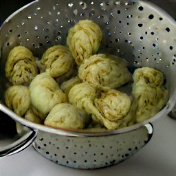 a can of artichoke hearts that have been rinsed and drained in a colander.