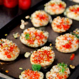 a dish of portabello mushrooms with tomatoes and parmesan cheese.