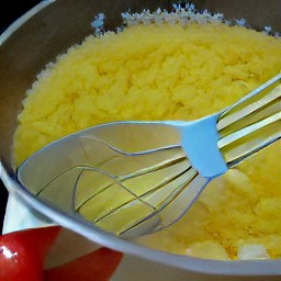 a bowl of whisked eggs with tabasco, grated potatoes and onions, and diced tomatoes.