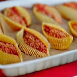 a dish with pasta shells, cheese mixture, and mozzarella cheese on top.