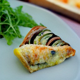 a piece of cheesy baked ratatouille with arugula salad.