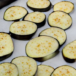 the eggplant slices are lined on a baking sheet with parchment paper and drizzled with 2 tsp of canola oil.