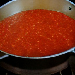 a pot of bubbling tomato sauce on the stove.