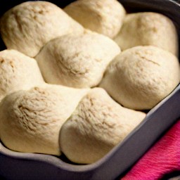 a greased loaf tin with braid dough inside, covered by a tea towel.