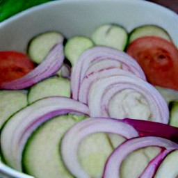 a bowl of sliced cucumbers, sliced onion, and tomatoes.