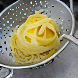 the cooked fettuccine pasta is drained in a colander.