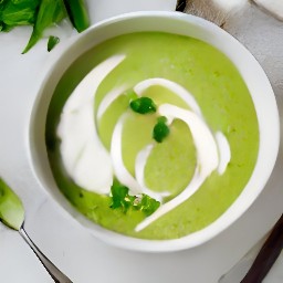 a bowl of cucumber, pea, and lettuce soup topped with plain yogurt and scallions.