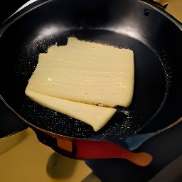 a skillet pan with cooked cheese slices.
