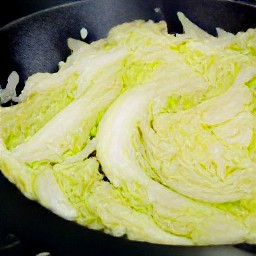 a wok full of sweet onions, brown sugar, and cabbage.