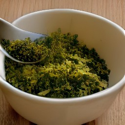 there a bowl of chopped parsley, hazelnuts, and lemon zest that are mixed together.