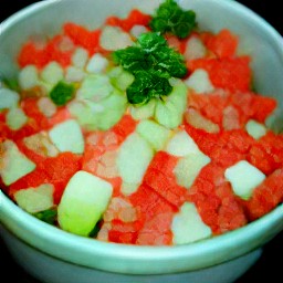 a bowl of chopped parsley, diced onions, cucumbers, and tomatoes mixed together with olive oil, lemon juice, and 1 tsp of salt.