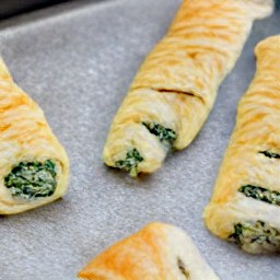 the baking tray contains cheese and spinach rolls.