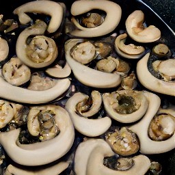 the sesame oil is drizzled over the skillet pan and stirred with a wooden spoon.