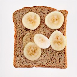 there are four slices of whole wheat bread, each with a sliced banana pressed down into the bread.