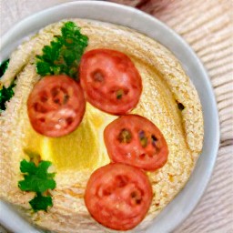 a bowl of soup garnished with tomato slices and parsley.