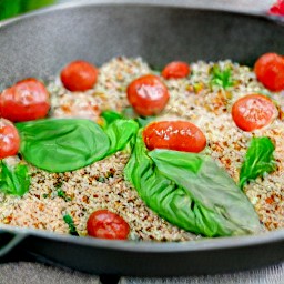 a quinoa mixture that is topped with spinach and cherry tomatoes.