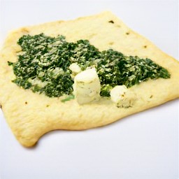 four spinach and cheese-filled puff pastry squares with egg wash on the corners.