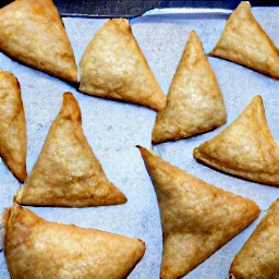 the baking sheet is taken out of the oven, revealing spinach and cheese samosa.