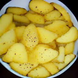 a bowl of chopped potatoes mixed with dried thyme, all purpose flour, 3 tbsp of olive oil, herbs and garlic seasoning, dried rosemary, and salt.