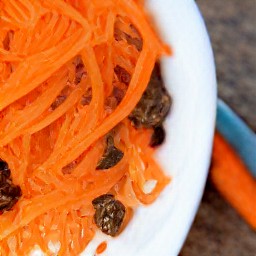 a bowl of raisins and shredded carrots mixed together.