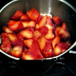 a heated saucepan with mashed strawberries.