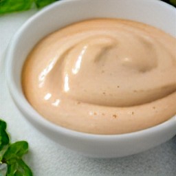 a bowl of mayonnaise, sour cream, and dried oregano with chopped red chili peppers.