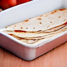 a third of the flour tortillas are laid in the baking dish, with half the tomato mixture on top.