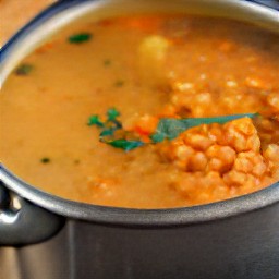a pot of simmering vegetable broth, red lentils, onions, potatoes, and garlic.