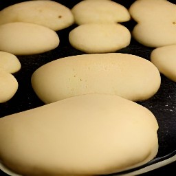 adding garlic mix to naans, putting naans on a baking tray, and adding chopped parsley and coriander to naans.