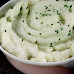 the cauliflower purée is transferred to a plate and scattered with grated cheddar cheese and chopped chives.