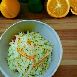 a bowl of mayonnaise, orange juice, sugar, salt, black pepper, cabbage, carrots, green bell peppers and raisins.