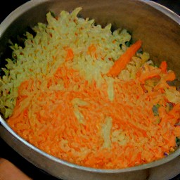 a large bowl of mixed grated cabbage, carrots, bell peppers, and red onions.