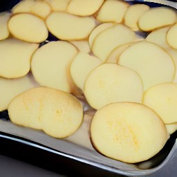 a baking tray with 2 tsp of butter and potato slices.