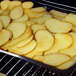 the baking tray is removed from the oven, revealing roasted potato slices.