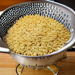 the cooked orzo pasta is drained in a colander.