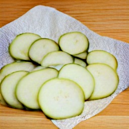 the zucchini slices are placed on a paper towel.