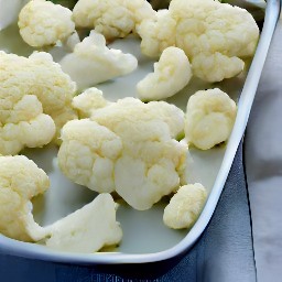 the cauliflower is placed in a baking dish.
