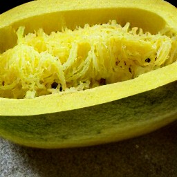 a bowl of spaghetti squash strings mixed with butter and parmesan cheese, seasoned with an eighth tsp of salt and an eighth tsp of black pepper.